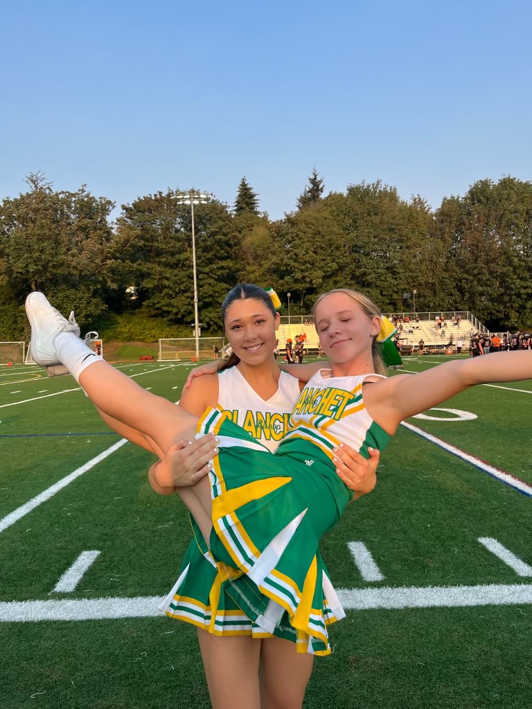 Junior cheerleader Avery Knutson celebrates the beginning of the season with support from teammate Caroline Eckhardt.